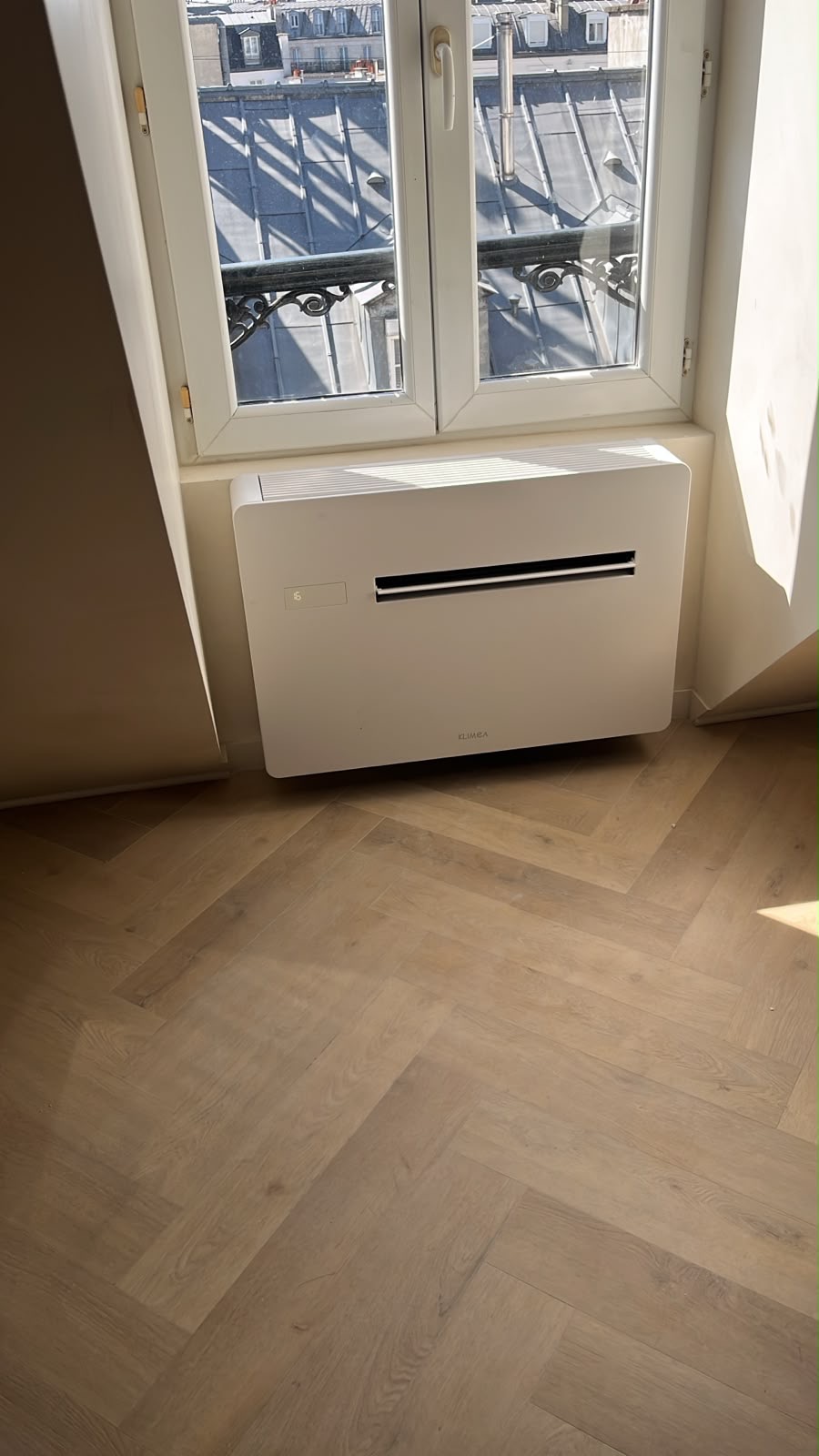 Console intérieure de climatisation installée au-dessus d'un parquet en chevrons