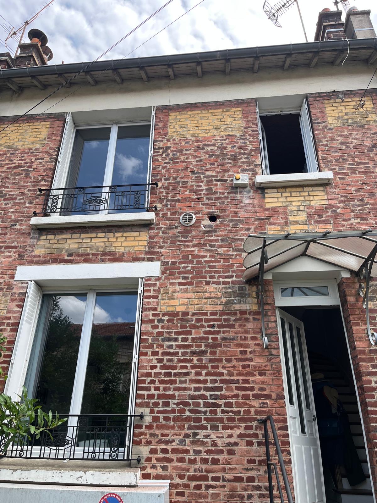 Percement réalisé dans une façade en brique pour une installation de climatisation