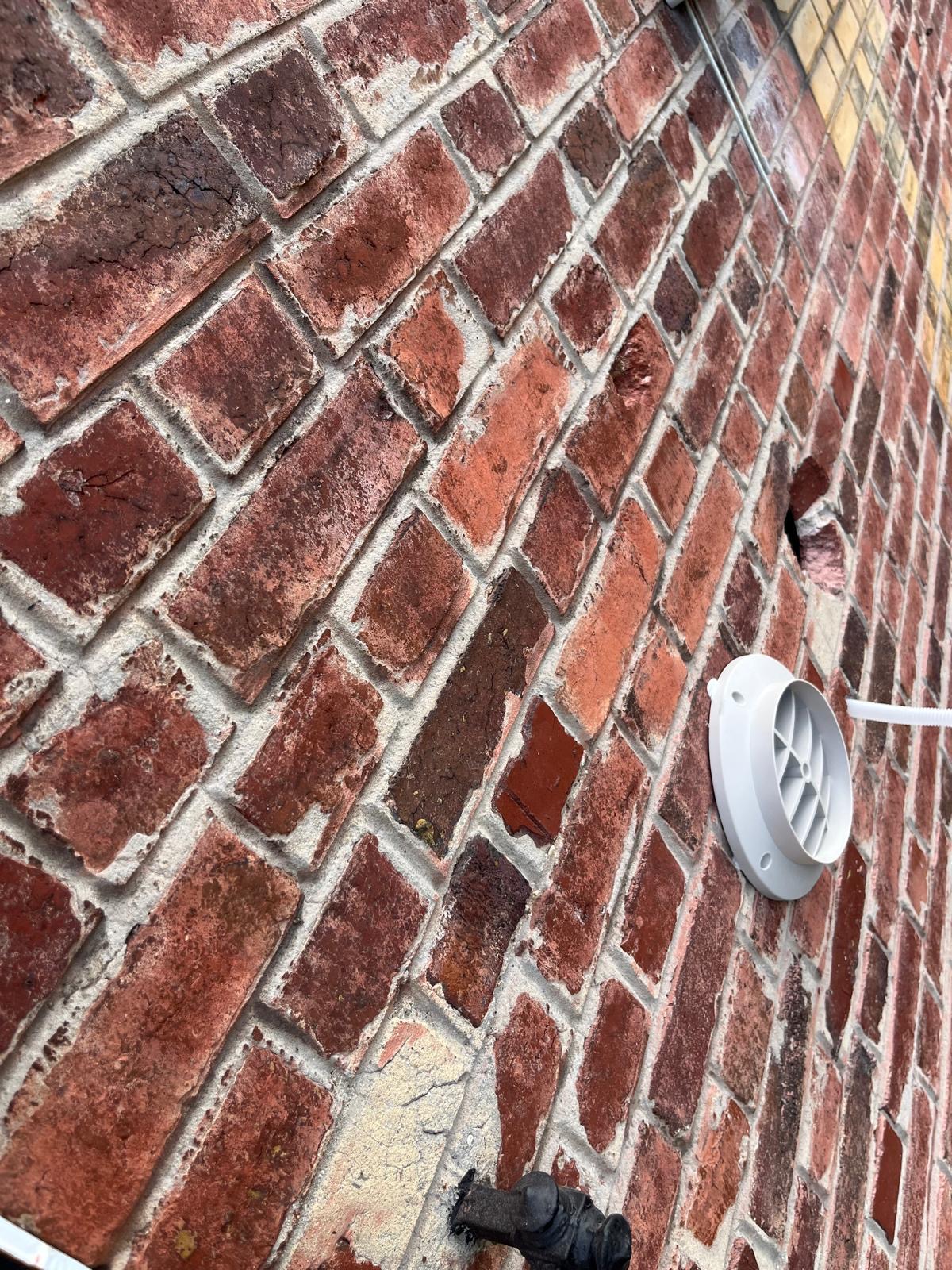 Grille extérieure de climatisation posée dans un mur en brique