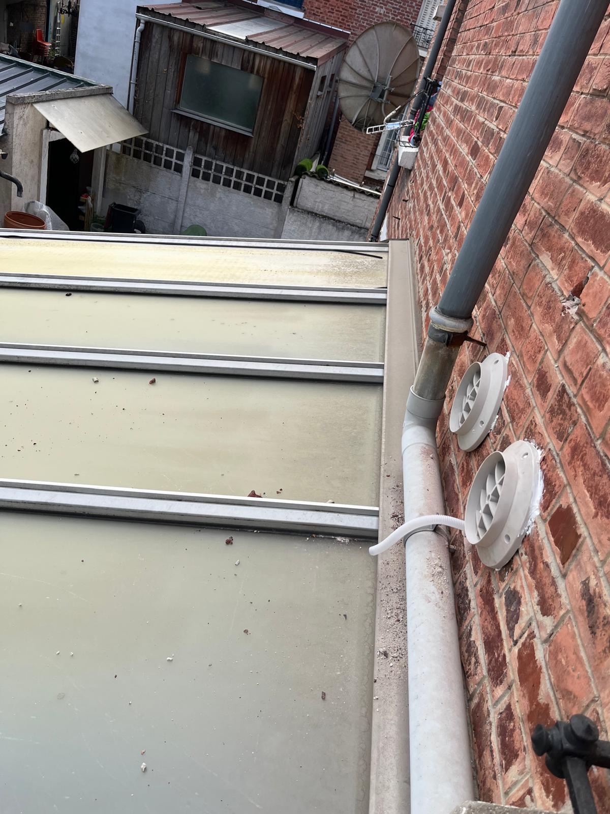 Grilles extérieures de climatisation posées sur un mur en brique