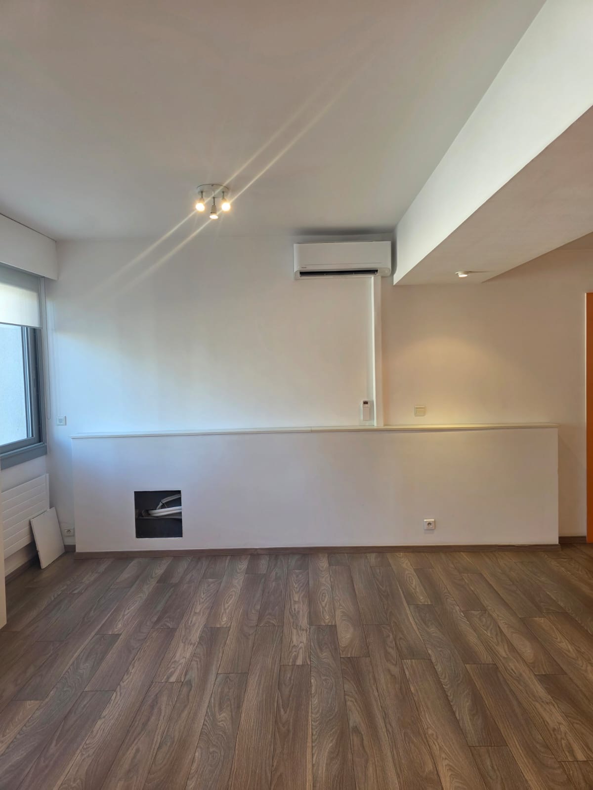 Split mural posé en haut d’un mur dans un logement vide, liaisons passant par une trappe encastrée